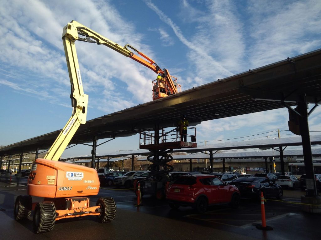 un gros camion orange garé à côté d'un grand bâtiment, une grue posée sur un camion